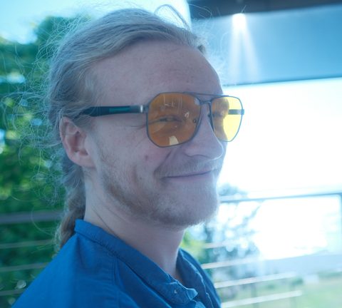 Bentley Perkins, smiling, in orange-tinted glasses, outdoors.